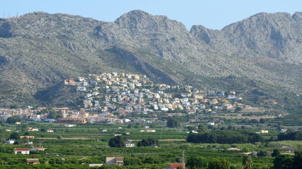 A town nestled in a valley with mountains in the background.