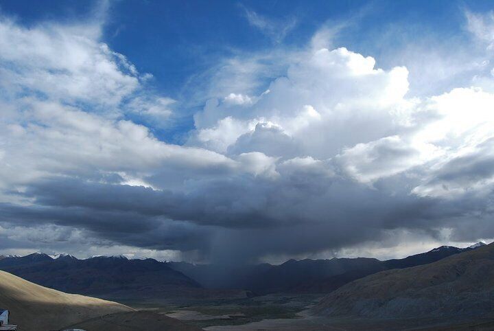 A mountainous landscape with a valley and a cloudy sky.