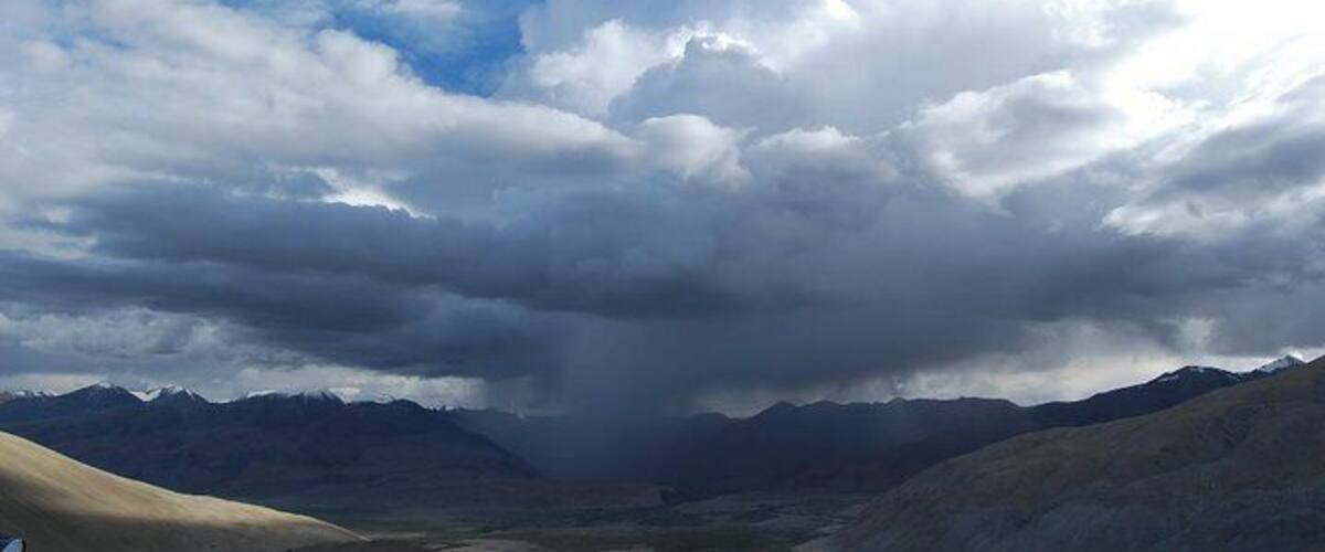 A mountainous landscape with a valley and a cloudy sky.