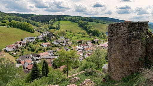 Ein historisches Dorf mit Steinhäusern, umgeben von üppigen grünen Feldern und einem markanten Steinturm.