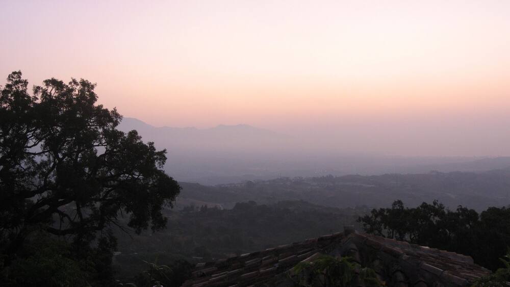 A misty landscape with a view of distant mountains and a clear sky.
