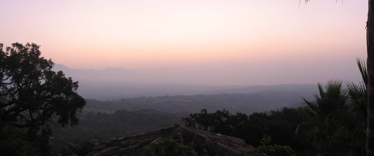 A misty landscape with a view of distant mountains and a clear sky.