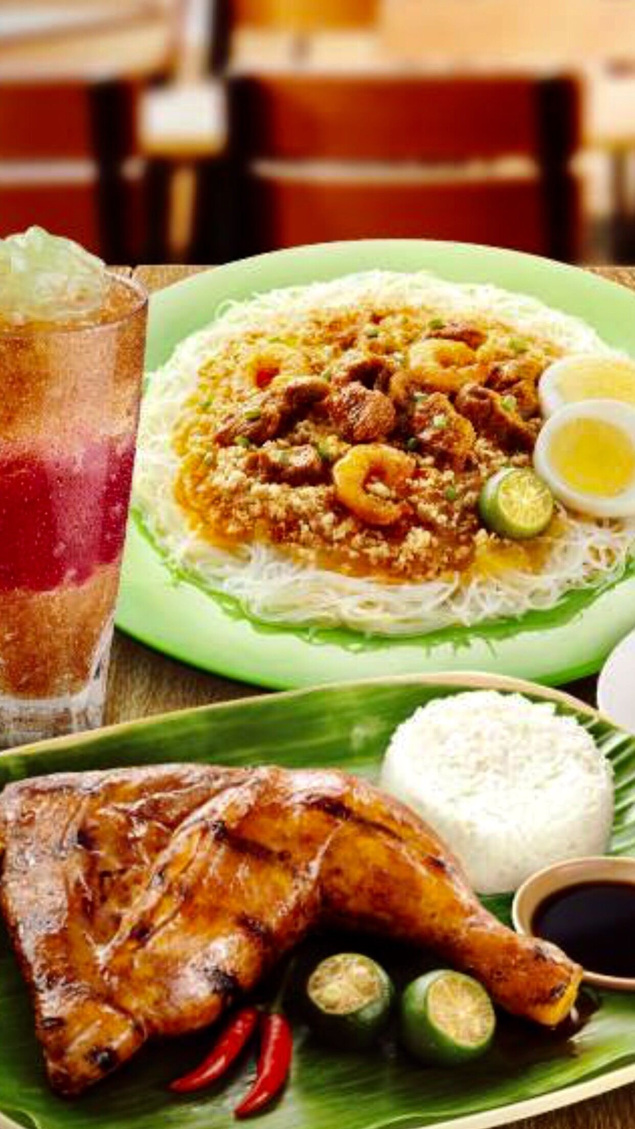 A plate of grilled chicken, a bowl of rice, and a dish with noodles and vegetables.