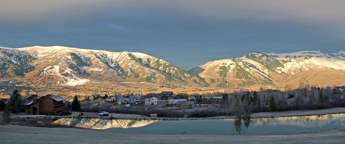 A lakeside town with snow-capped mountains in the background.