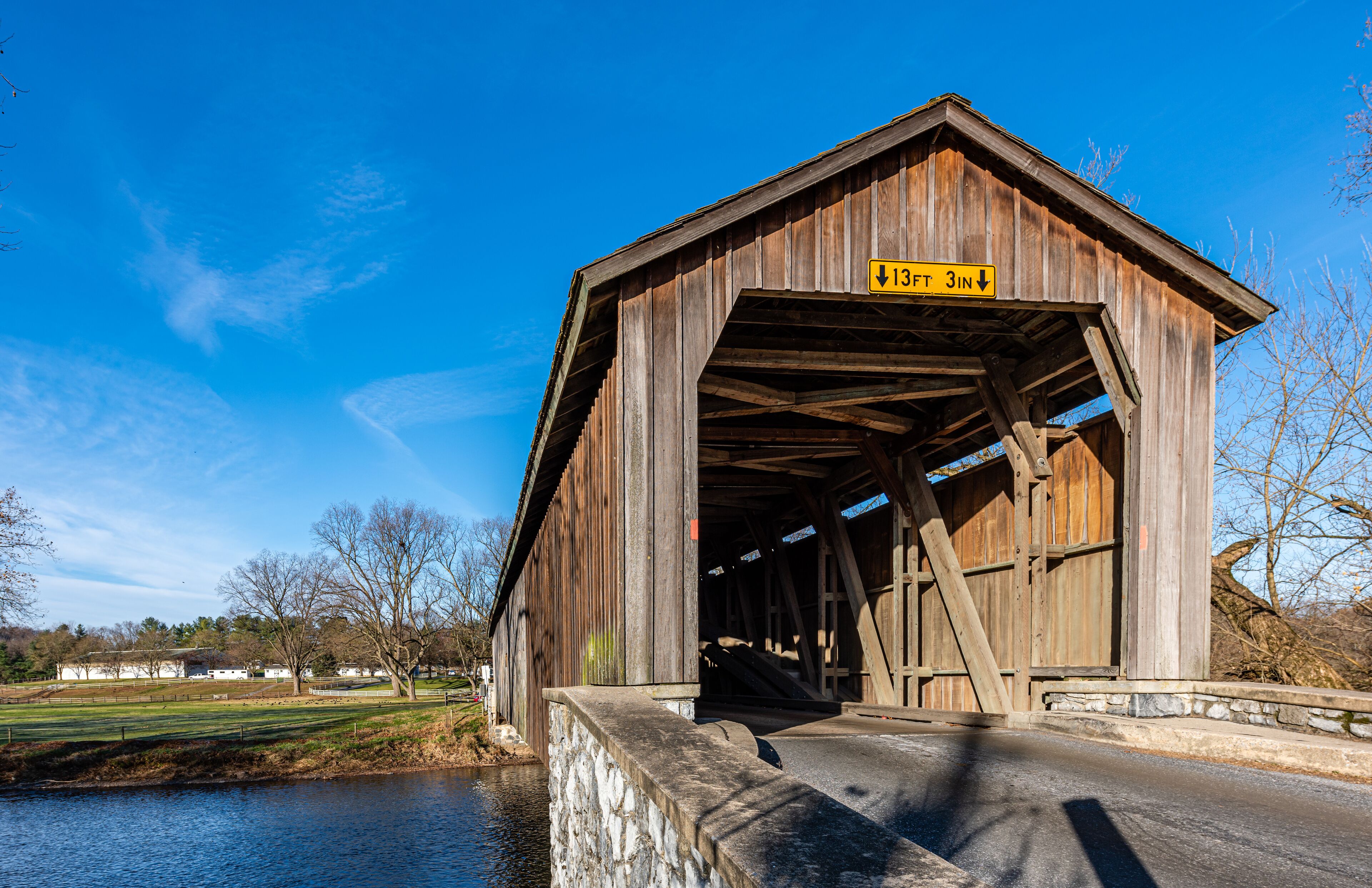A wooden covered bridge with a sign indicating a height clearance of 13 feet 3 inches.