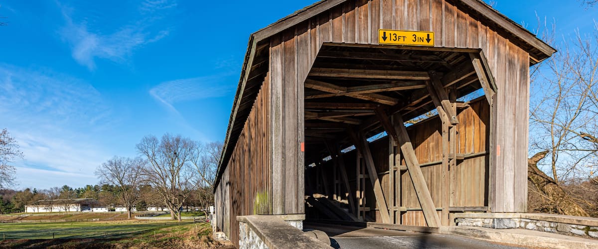 A wooden covered bridge with a sign indicating a height clearance of 13 feet 3 inches.