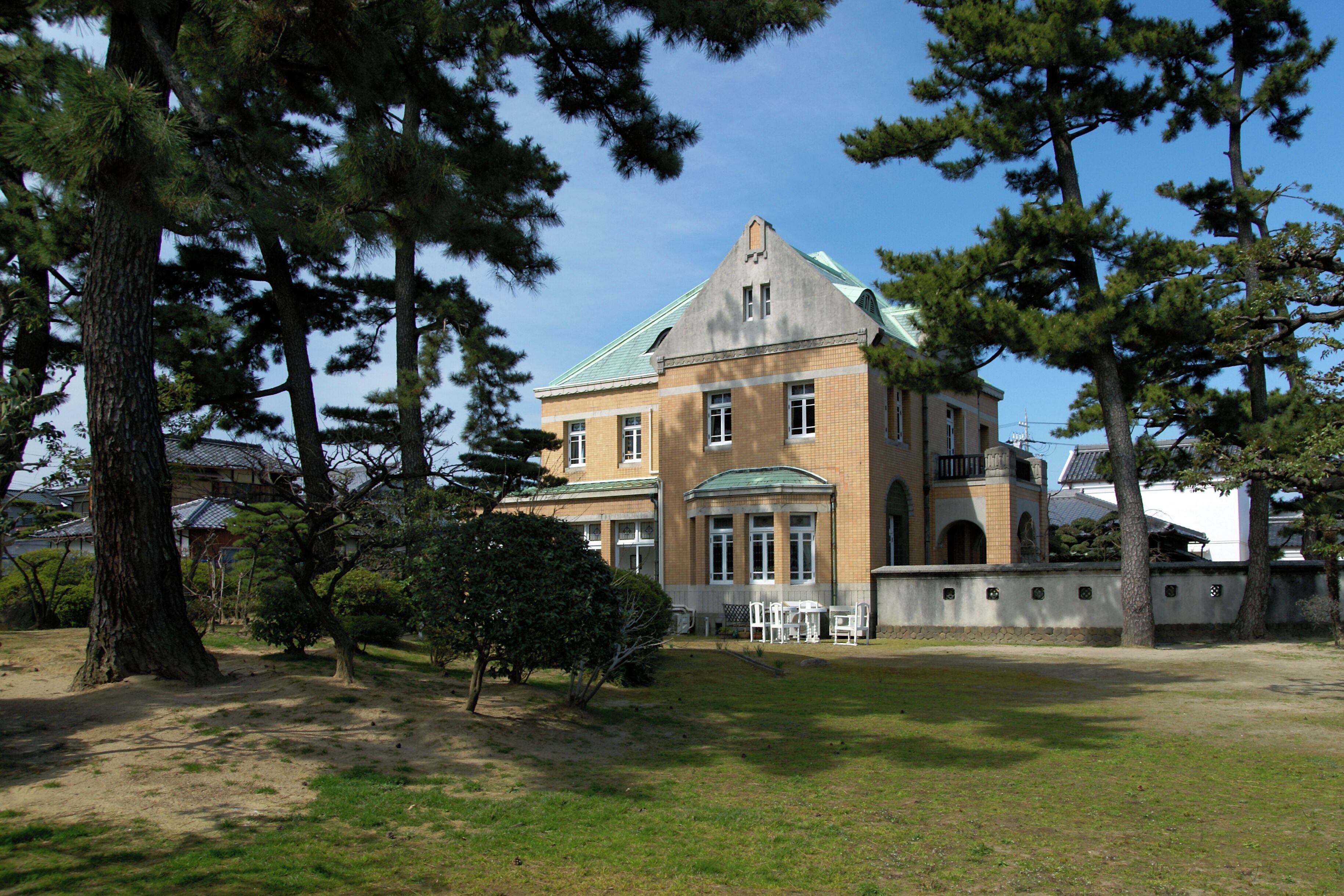 A large building with a green roof, surrounded by trees and a grassy area.