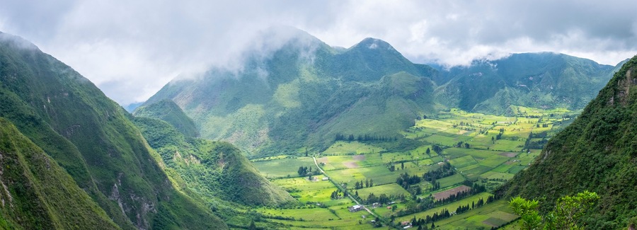 A valley with terraced fields and mountains in the background.
