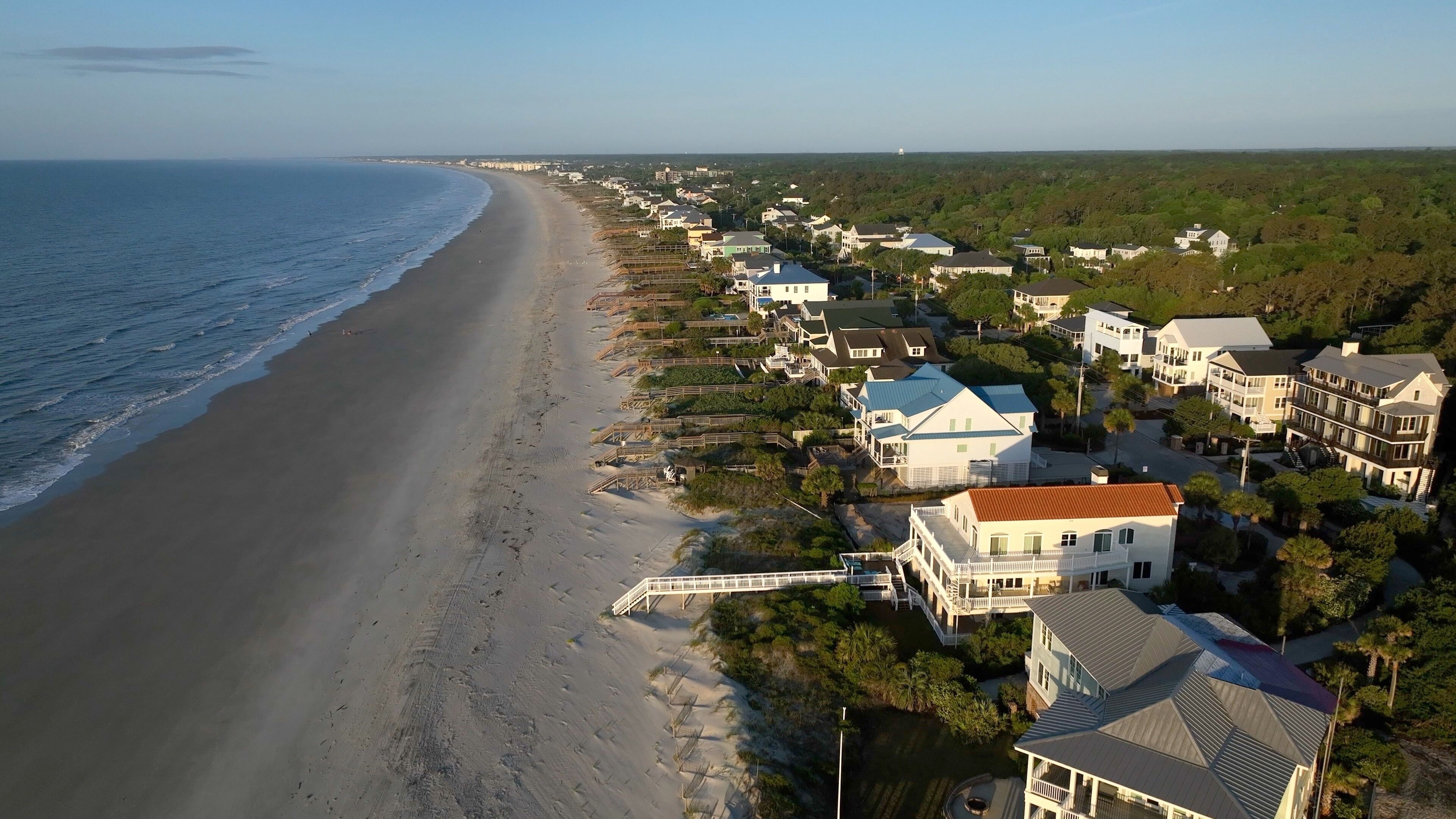 A coastal residential area with houses along the beach and a clear view of the ocean.