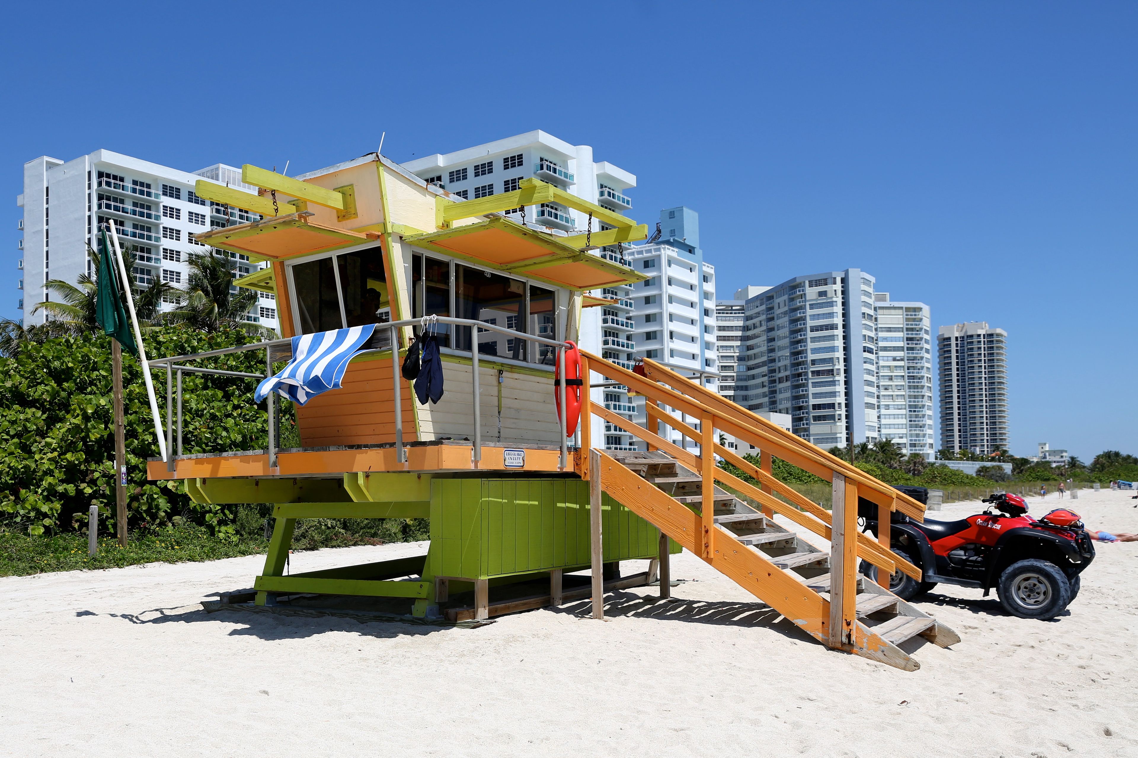 A lifeguard tower on a beach with a red ATV parked nearby.