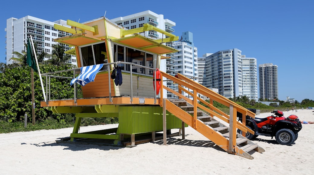 A lifeguard tower on a beach with a red ATV parked nearby.