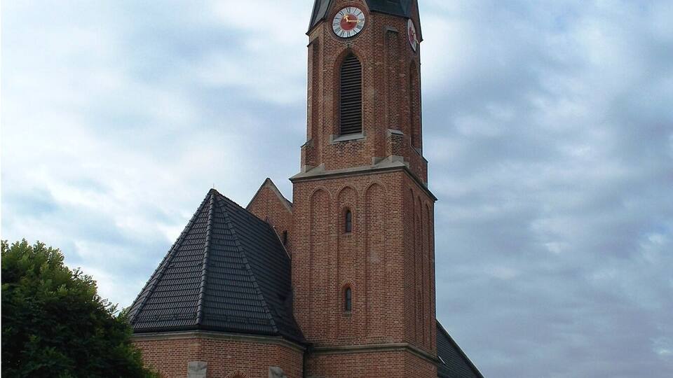 A brick church with a tall steeple and a clock.