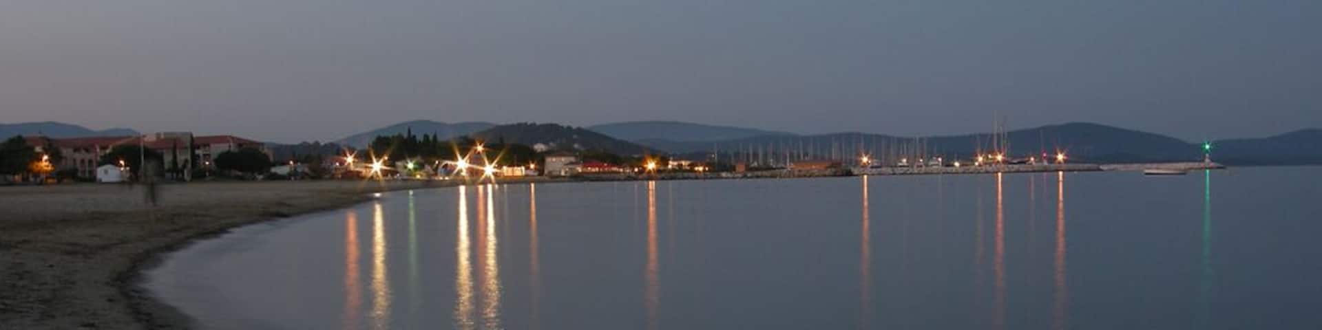 La mer avec le port du Miramar, la nuit.