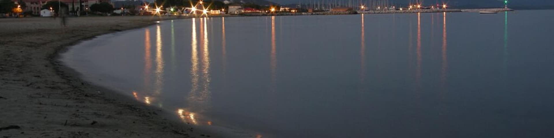 La mer avec le port du Miramar, la nuit.
