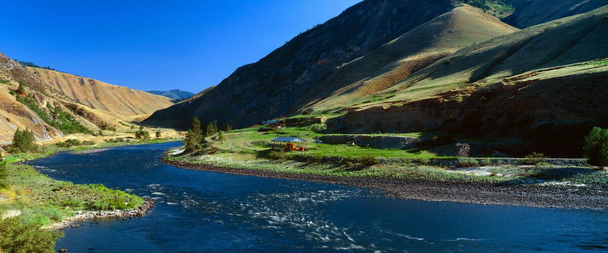 A river winding through a valley with steep, rocky mountains on either side.