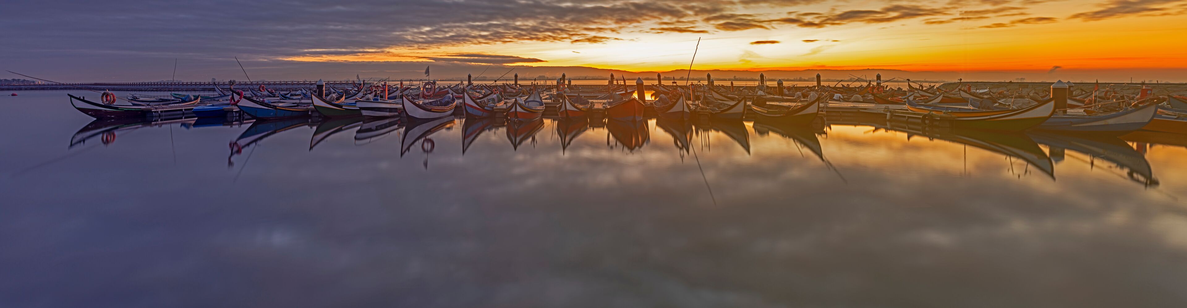 A marina with numerous boats at sunset.