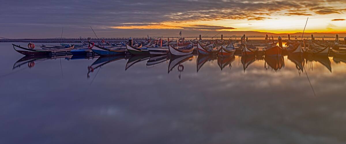 A marina with numerous boats at sunset.