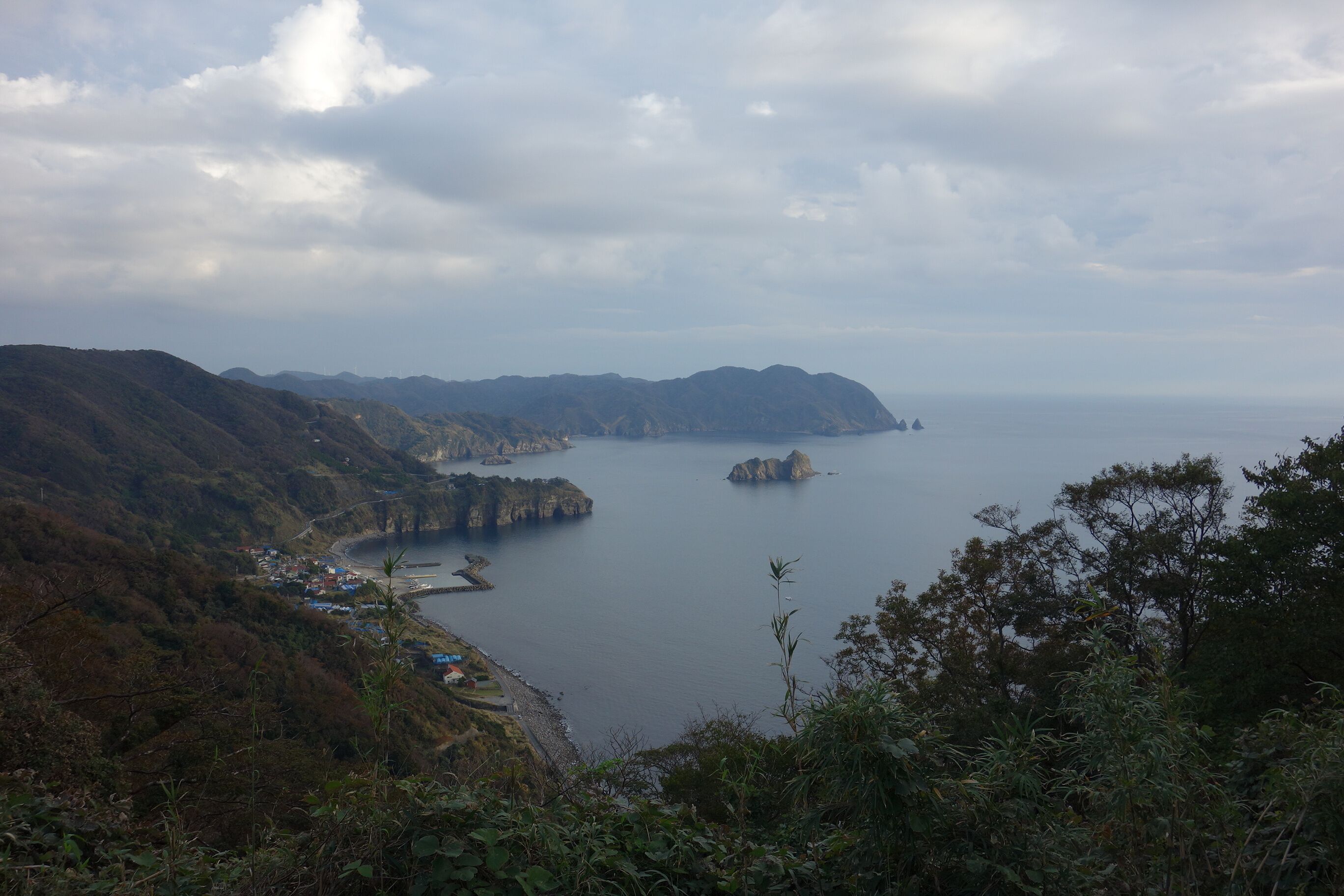 A coastal landscape with mountains, a bay, and a small settlement.