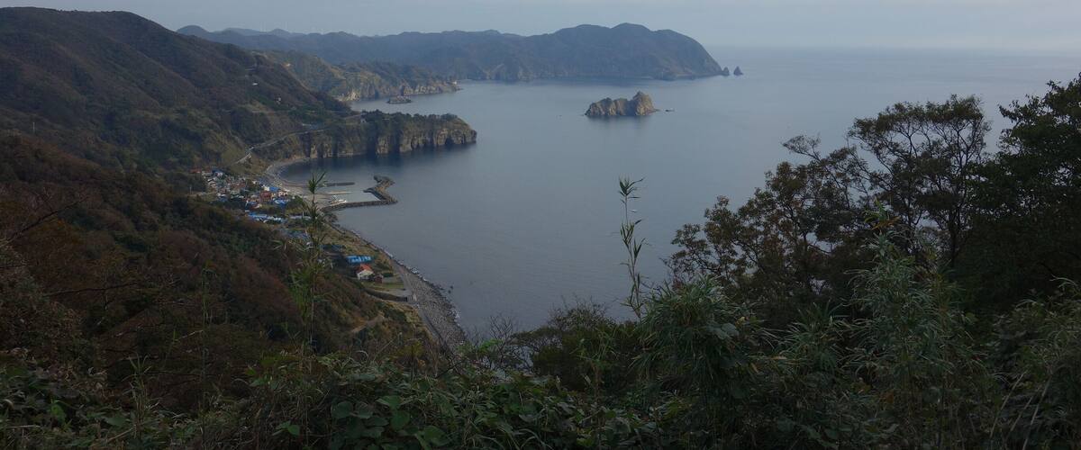 A coastal landscape with mountains, a bay, and a small settlement.