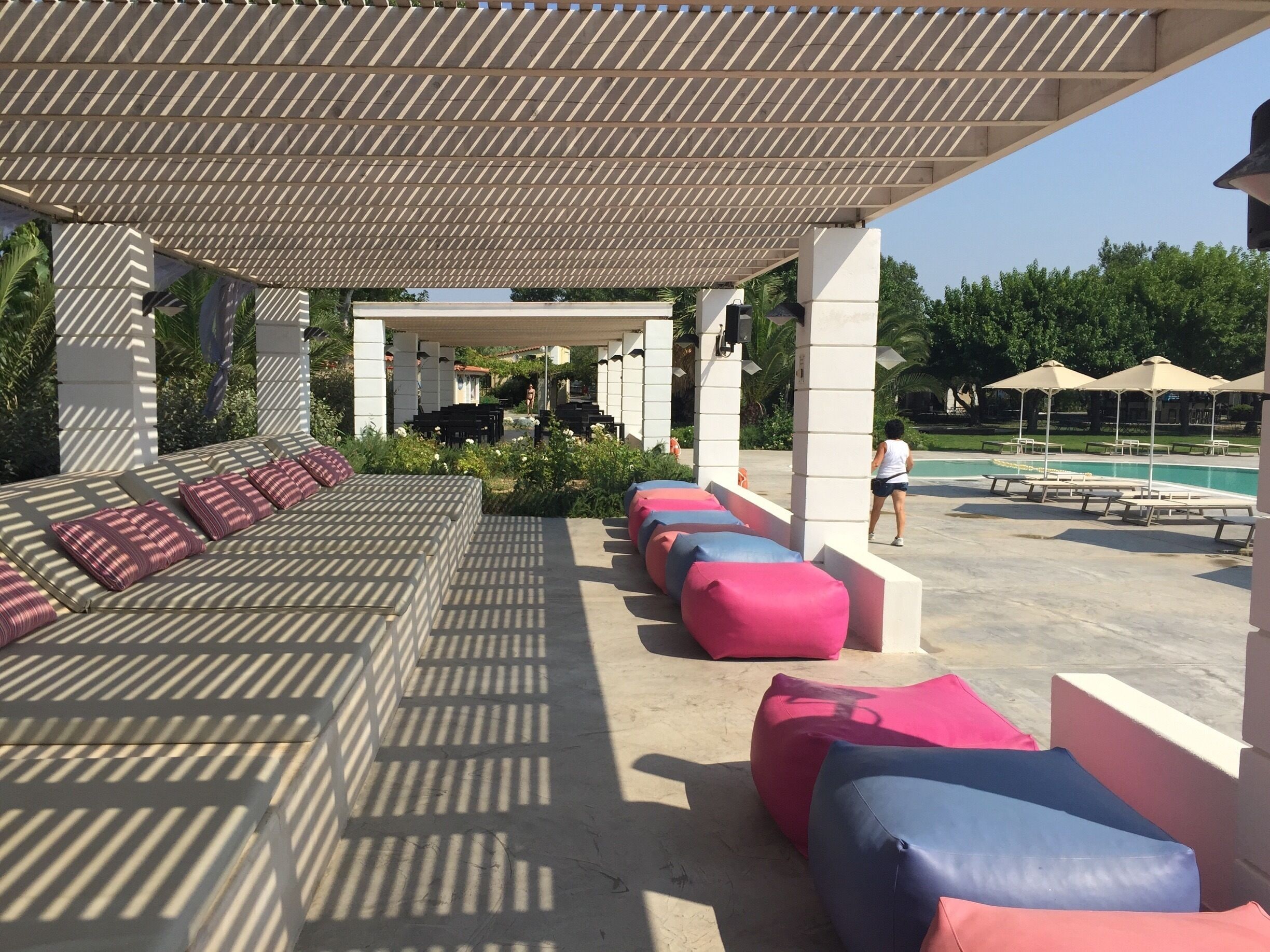 A covered outdoor seating area with patterned cushions and a pool in the background.