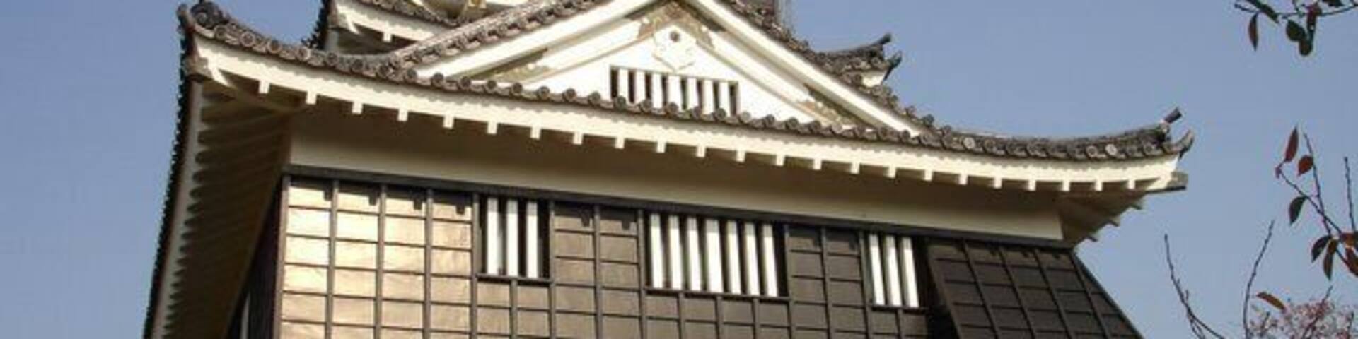 A traditional Japanese castle with a stone base, tiled roof, and multiple tiers.