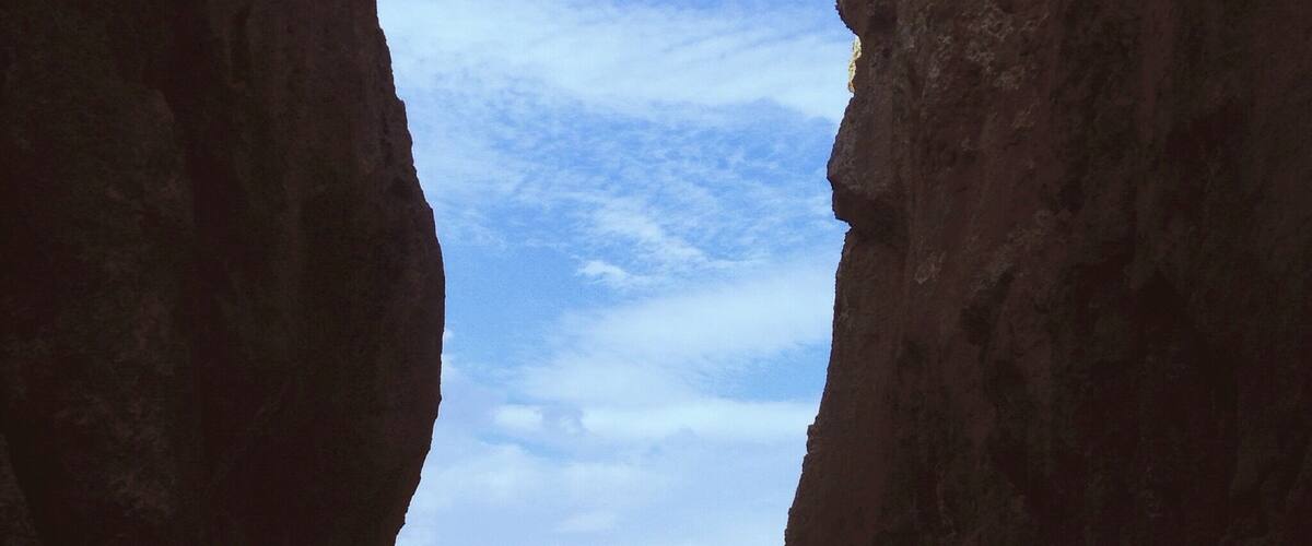 A beach framed by large rock formations with a view of the ocean.