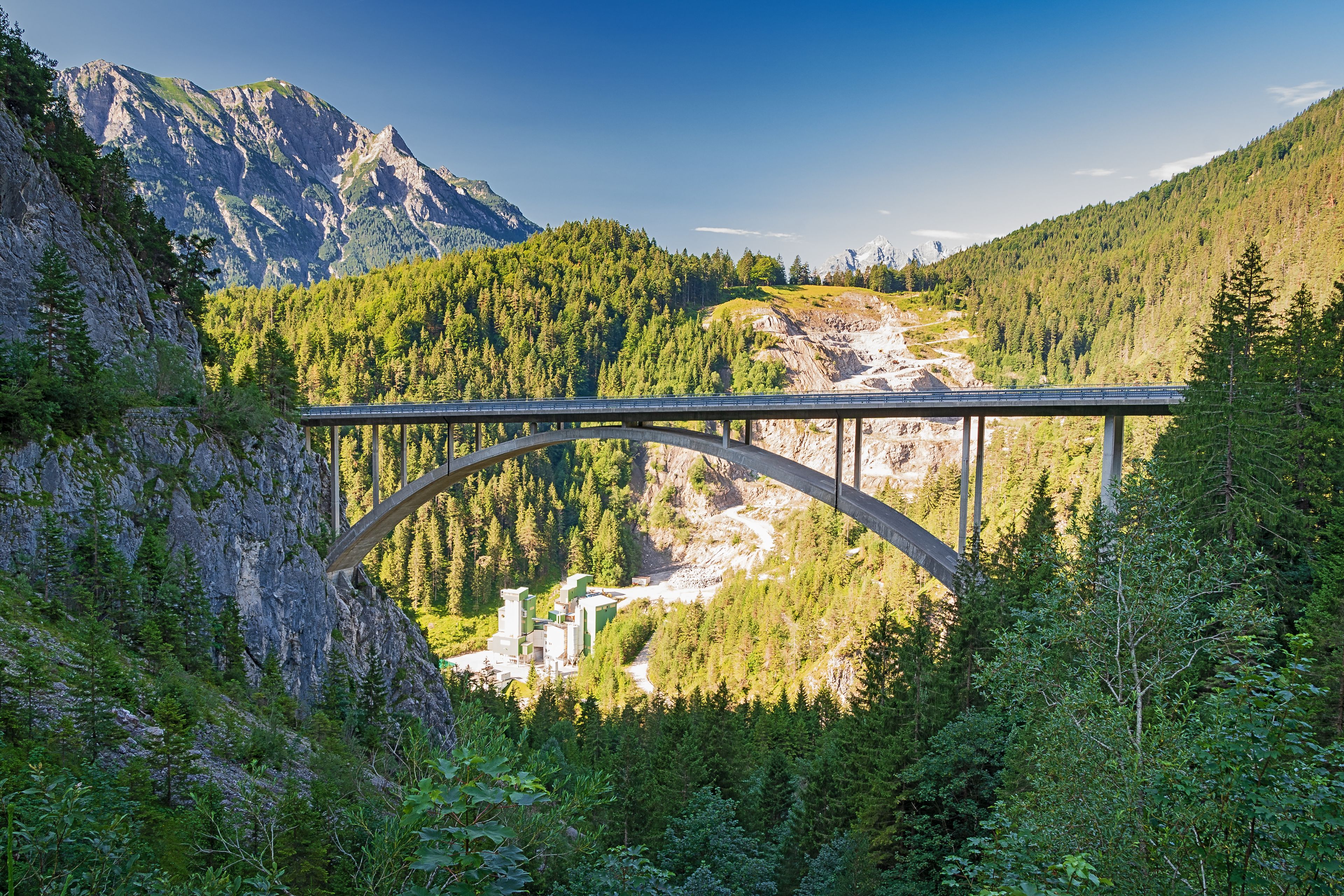 Eine Brücke über einem Fluss, im Hintergrund Berge.