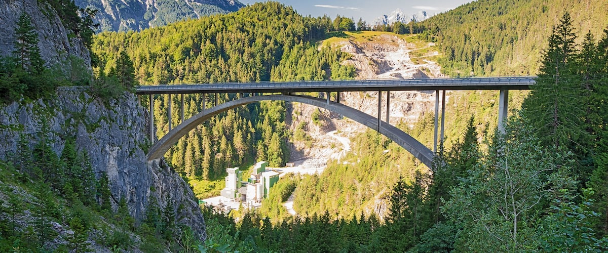 Eine Brücke über einem Fluss, im Hintergrund Berge.