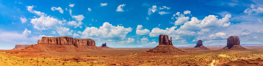 Un paysage désertique caractérisé par des formations rocheuses rouges et un ciel bleu azur.