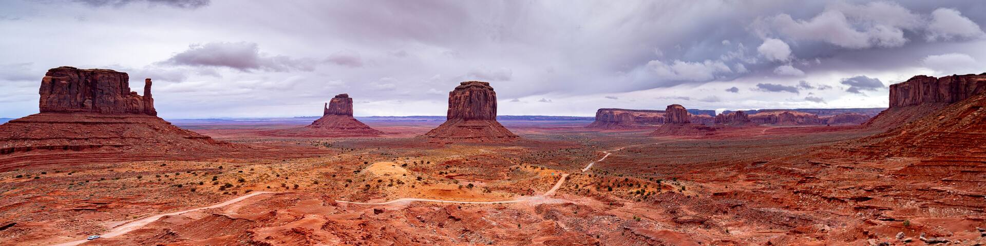 A desert landscape with prominent red rock formations and a dirt road.