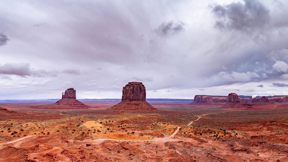 A desert landscape with prominent red rock formations and a dirt road.