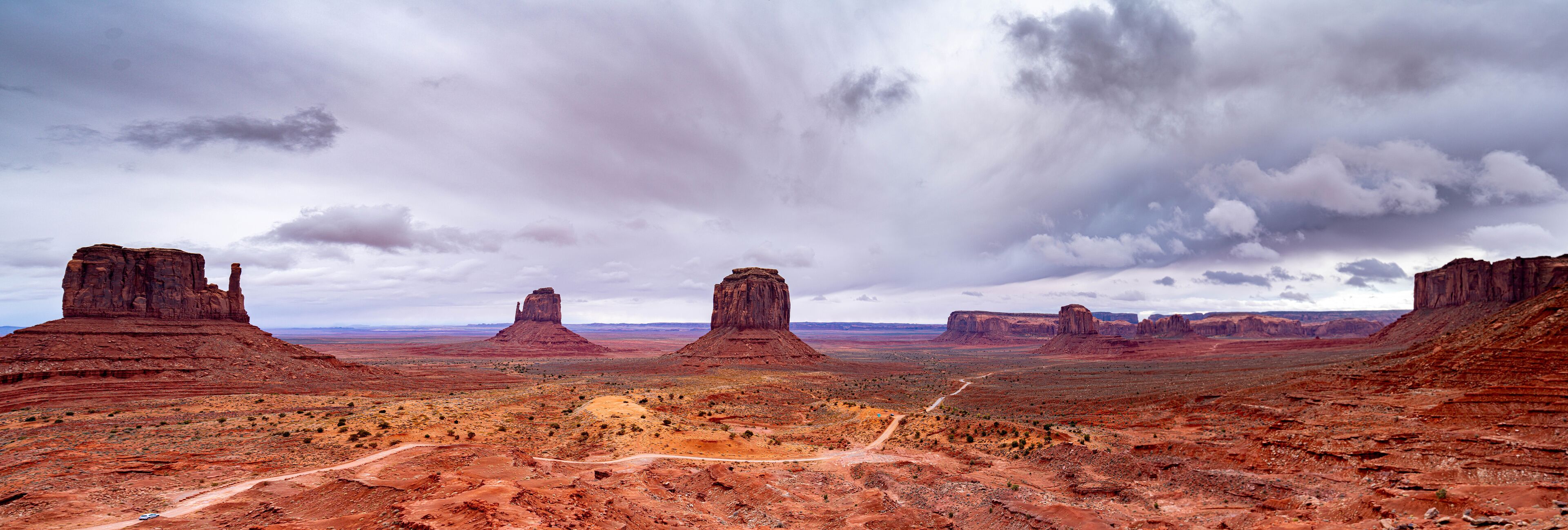 A desert landscape with prominent red rock formations and a dirt road.