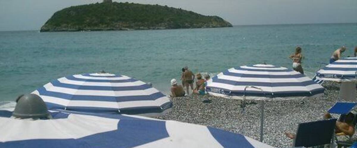 A beach with striped umbrellas and a small island in the background.