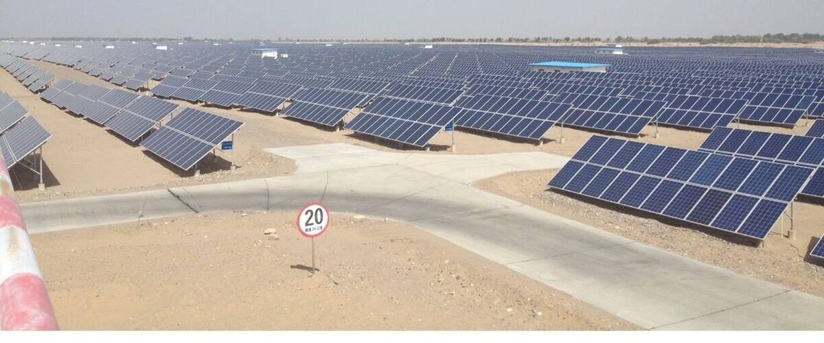 A large solar farm with rows of solar panels under a clear sky.