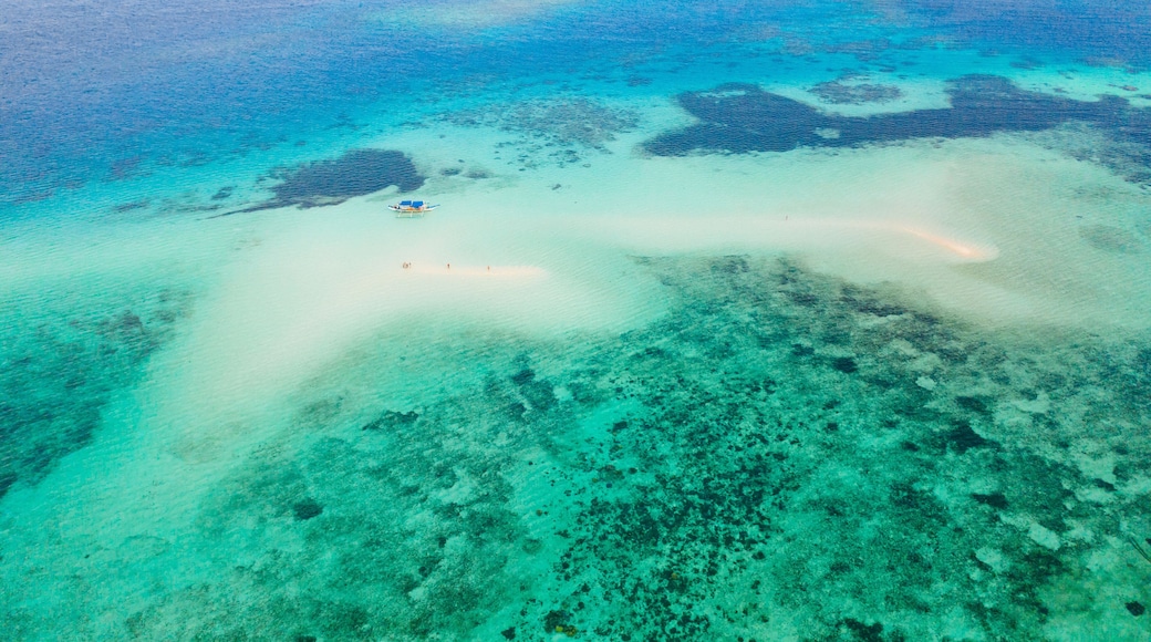 An aerial view of a turquoise sea with a small island and clear shallow waters.