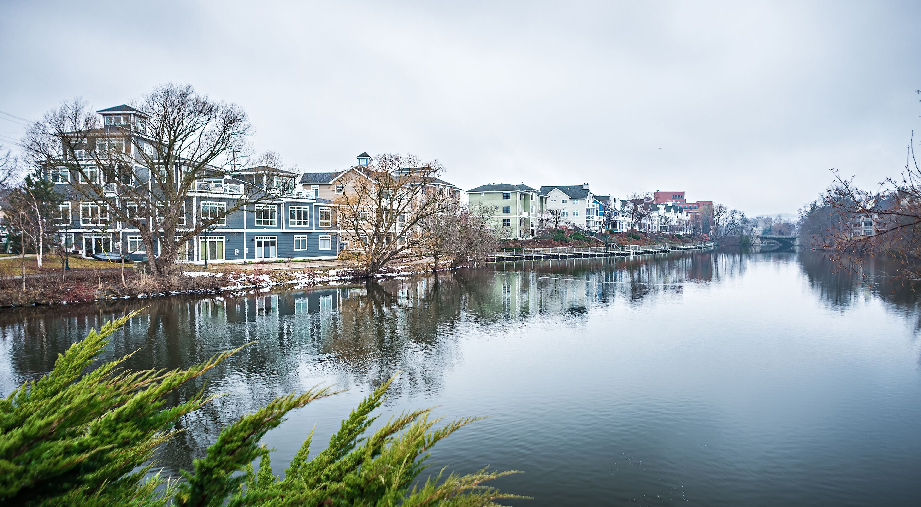 A calm river with reflections of buildings and trees.