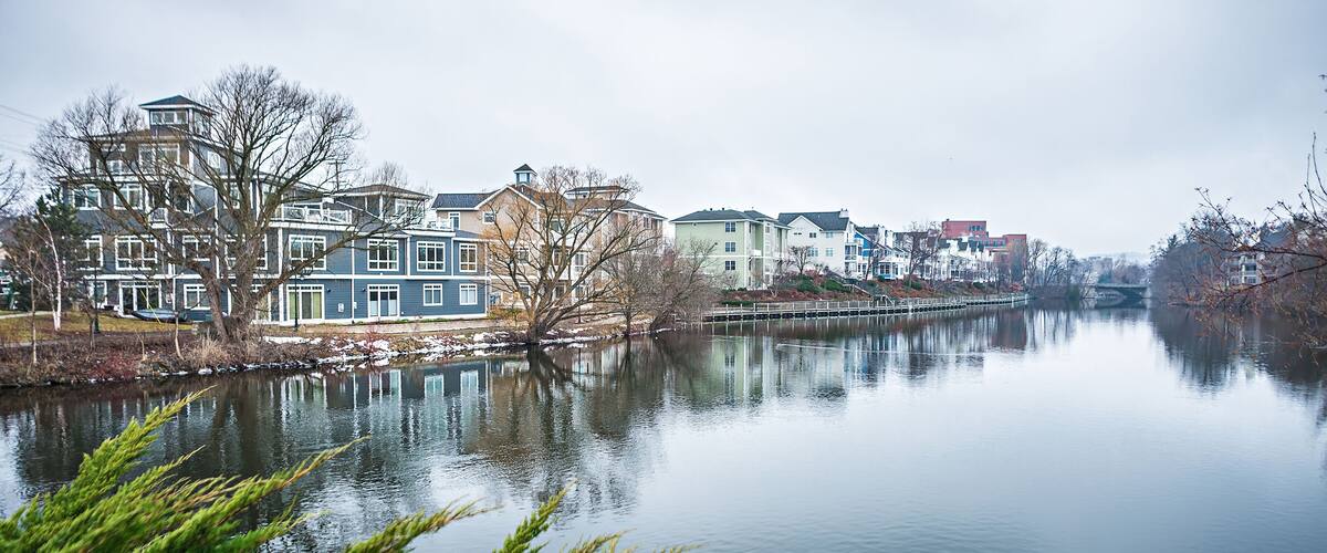 A calm river with reflections of buildings and trees.