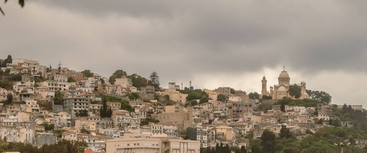 Une ville densément peuplée, nichée sur une colline, avec une église imposante qui domine le paysage.