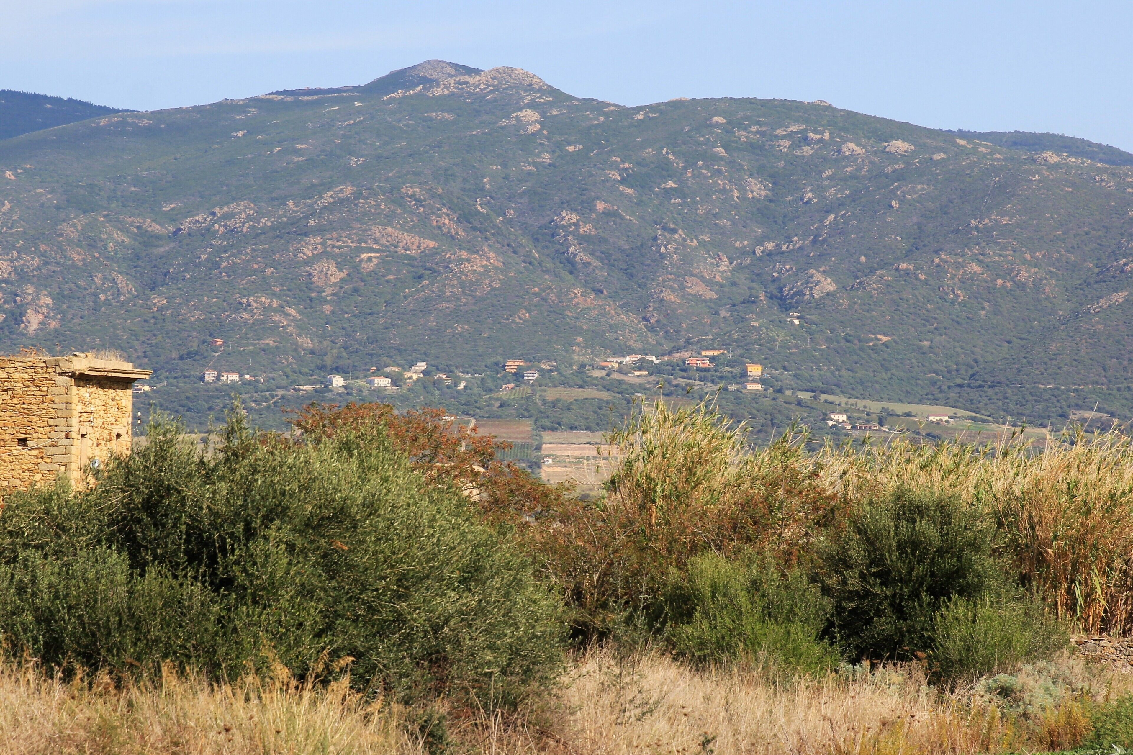 A mountainous landscape with a stone building in the foreground and a village in the background.