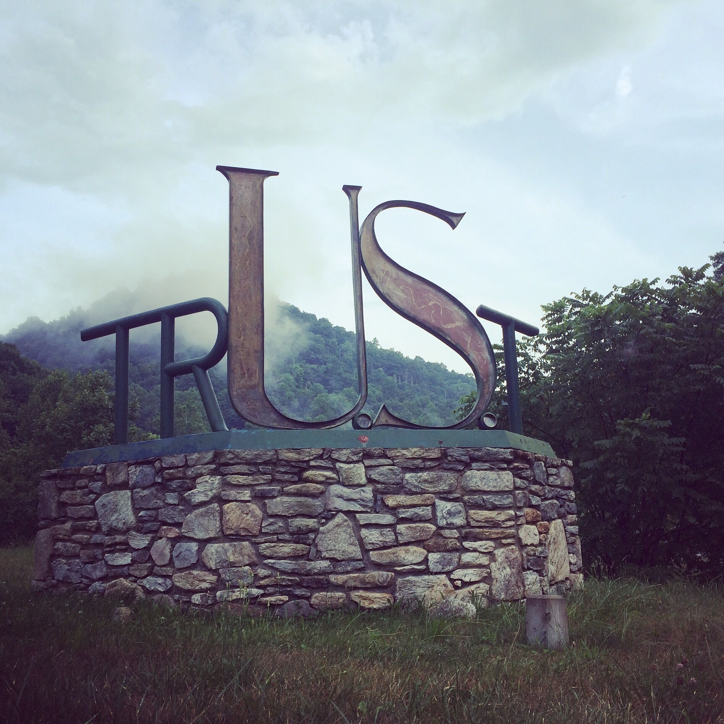 A stone wall with the word "TRUST" in large letters.