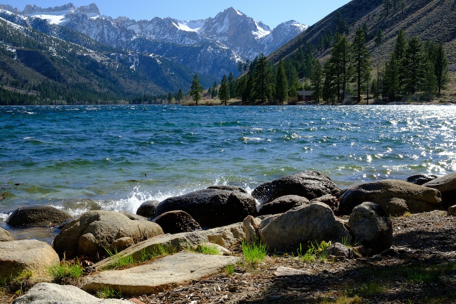 Un lago con aguas cristalinas, rodeado de grandes rocas y montañas al fondo.
