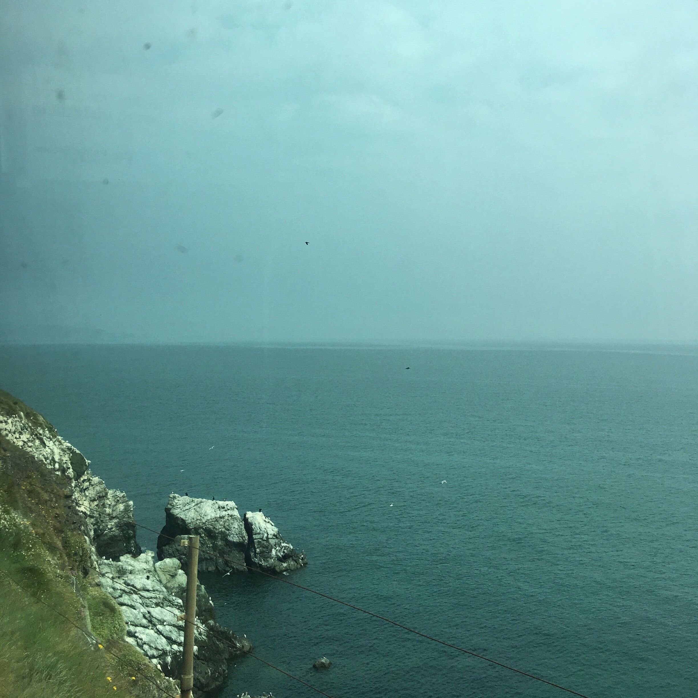 A coastal landscape with rocky cliffs and a calm sea.