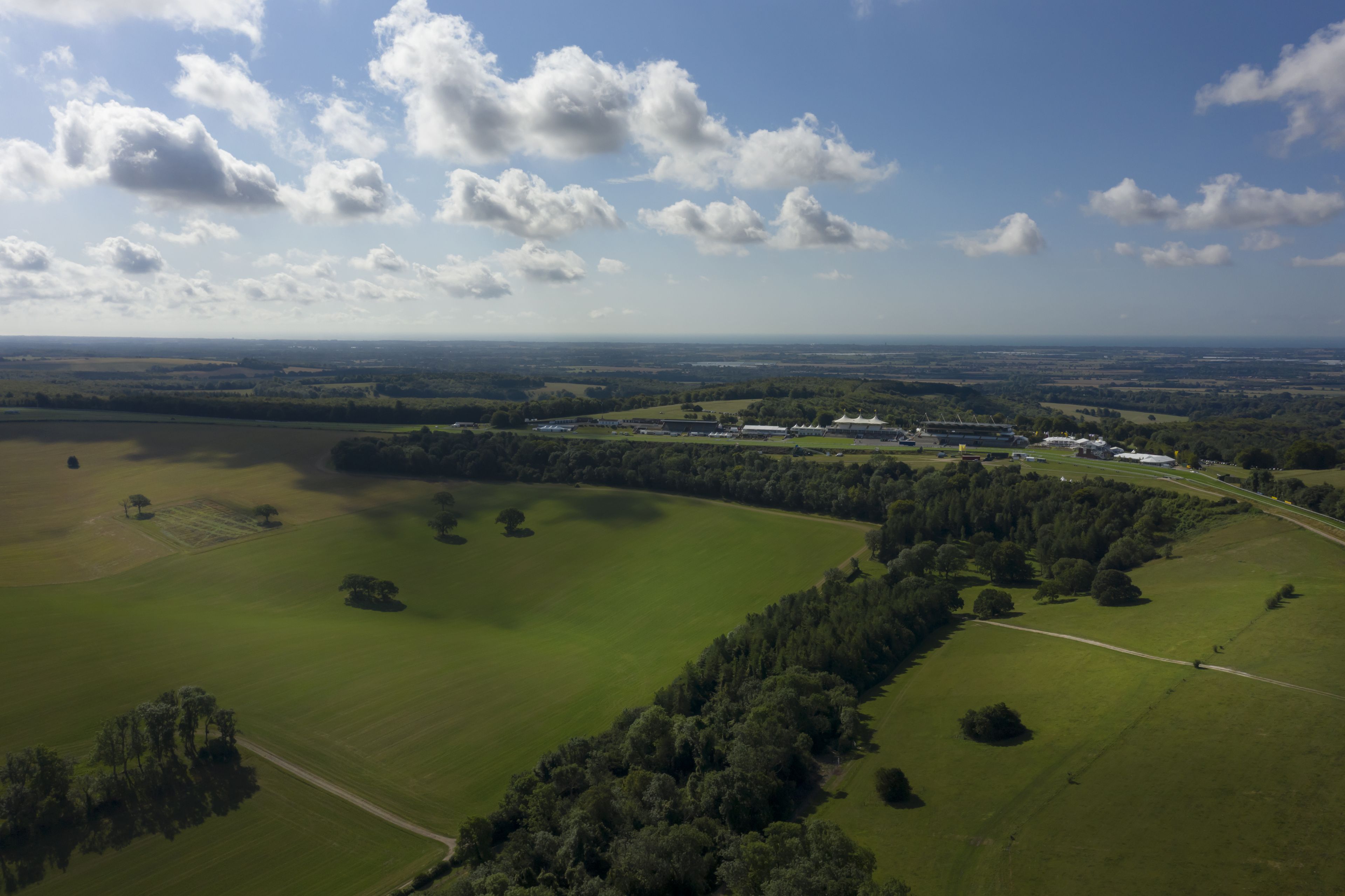 Paisagem rural com campos, árvores e um grande complexo de edifícios brancos.