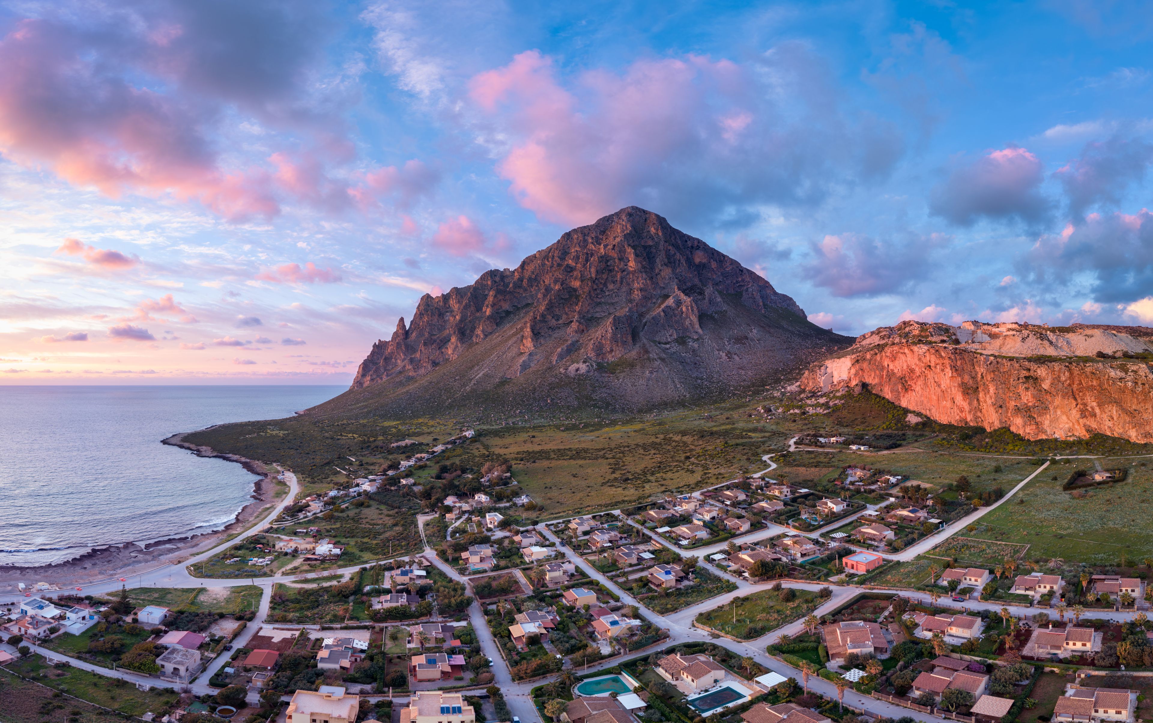 A coastal town with a prominent mountain, winding roads, and residential buildings.