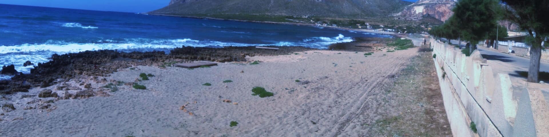 A beach with a rocky mountain in the background.