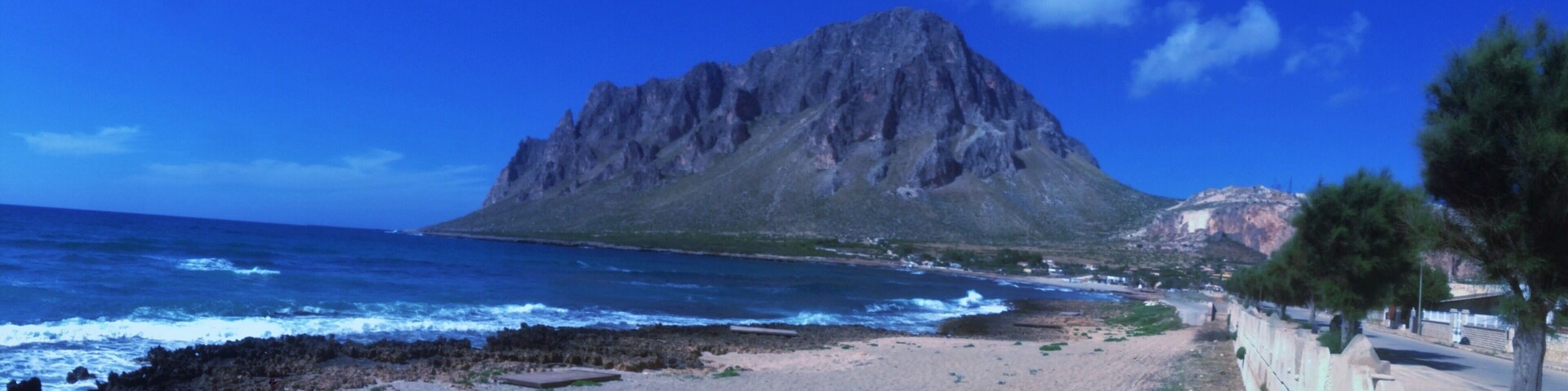 Una playa con una montaña rocosa al fondo.