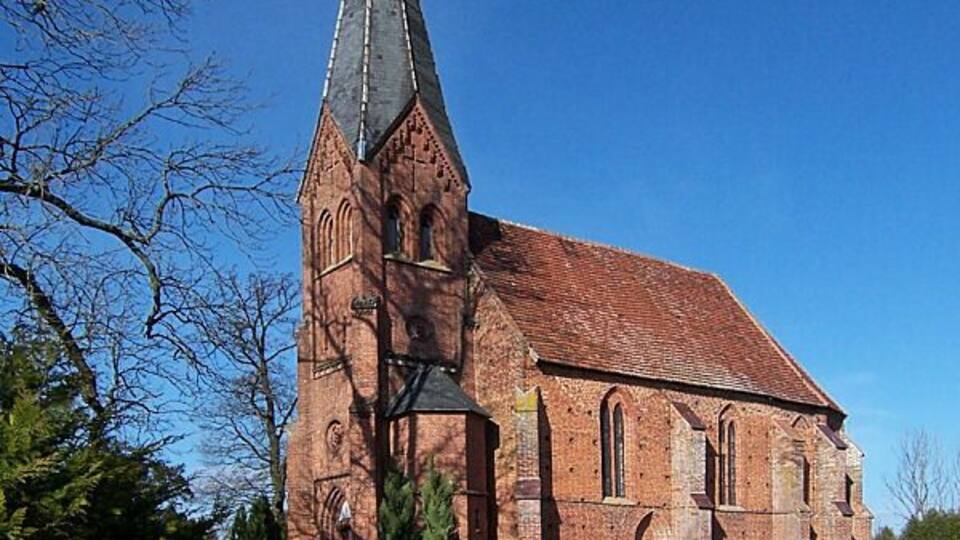 A red brick church with a tall steeple and arched windows.
