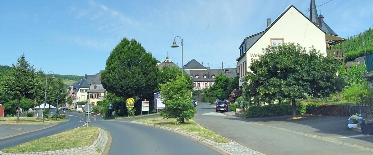 A sunny street in a small town with a church, a hotel, and a sign for a restaurant.