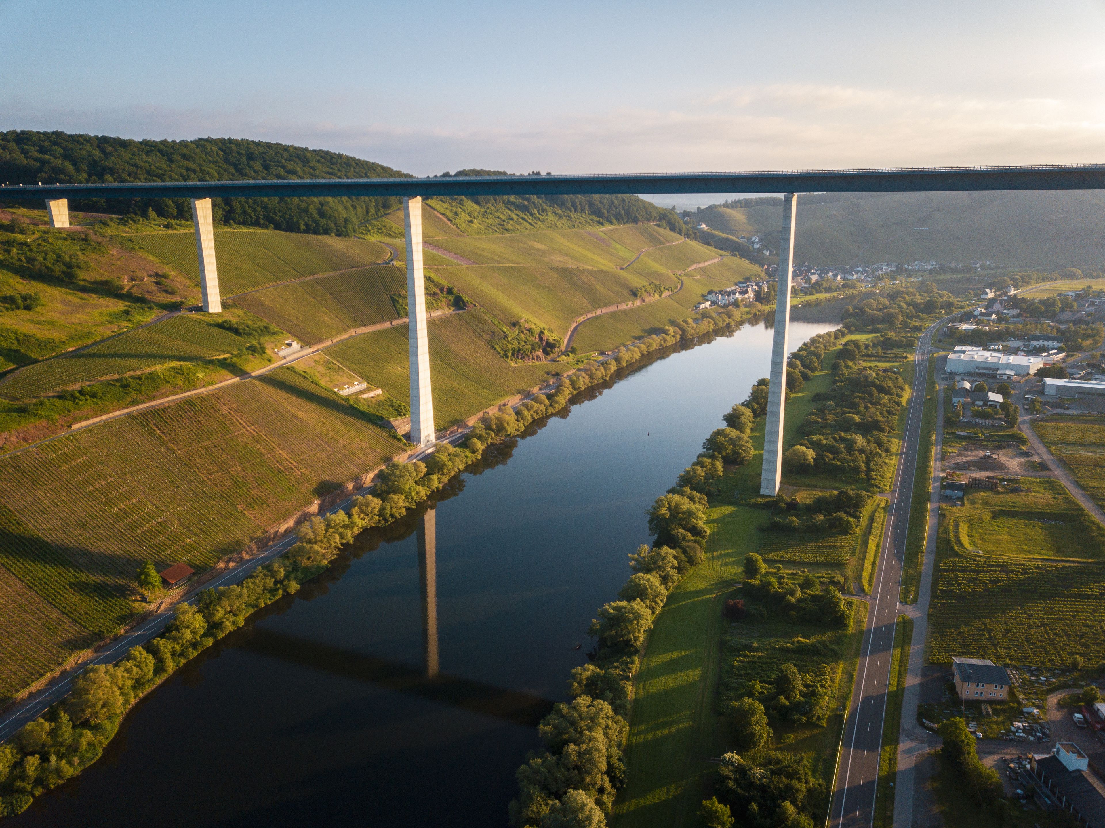 Une rivière traversée par un pont, des champs verdoyants et une petite ville.