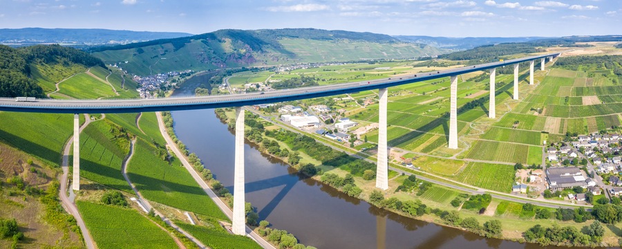 A long bridge spanning a river, surrounded by green fields and small buildings.